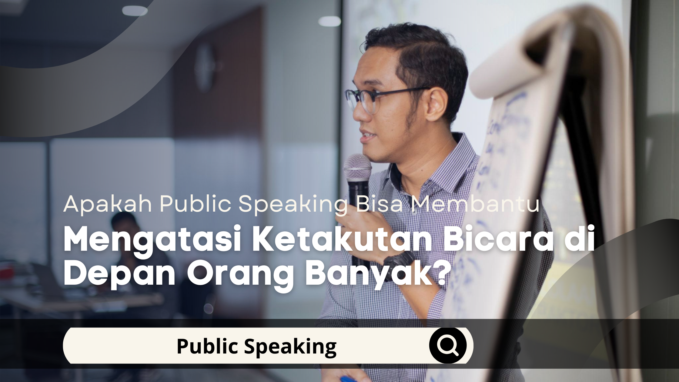 Seorang pria sedang berlatih public speaking menggunakan mikrofon di depan peserta dalam suasana pelatihan.